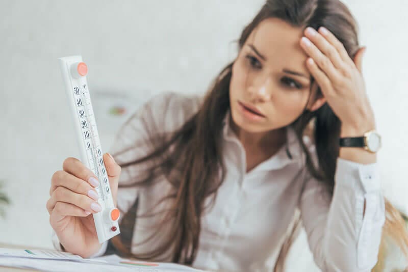 暑すぎるオフィスに頭を抱える女性